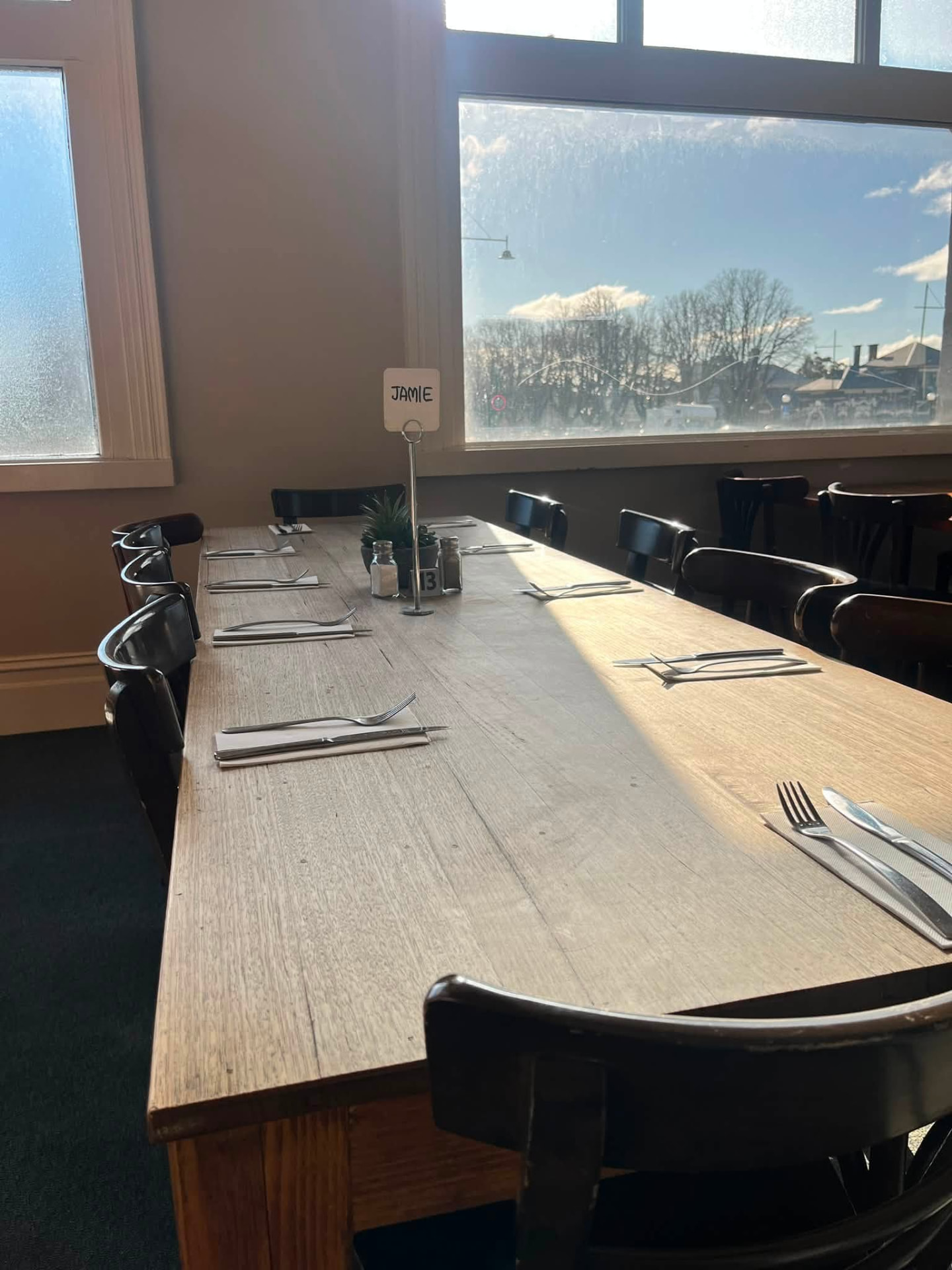 Long timber table set for a group beside the window