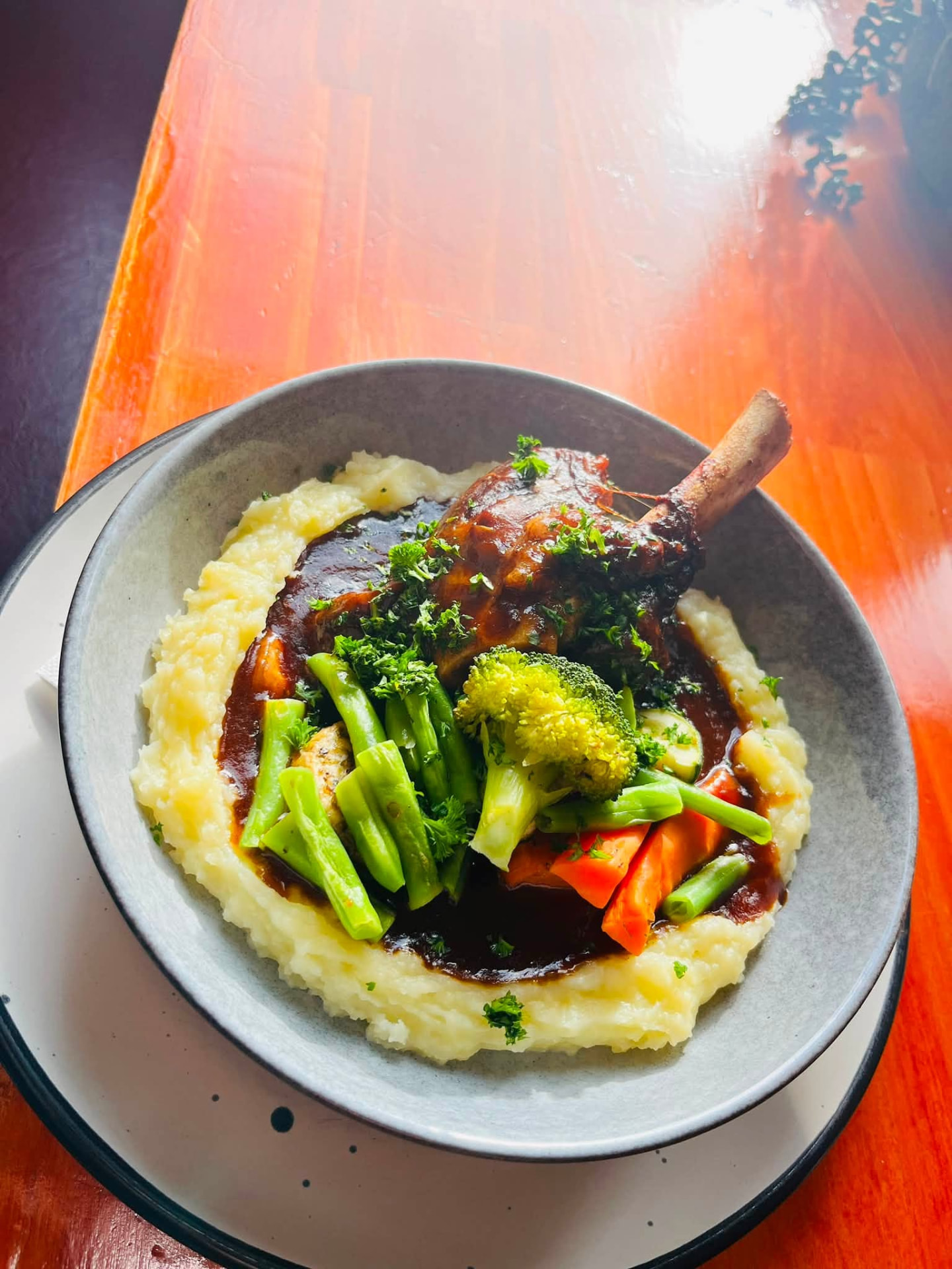 Braised lamb shank on creamy mash with greens and jus